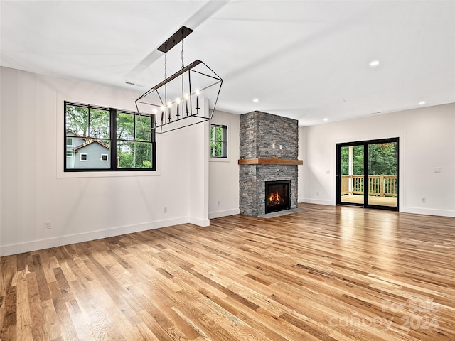 unfurnished living room featuring light hardwood / wood-style flooring, a fireplace, and a chandelier