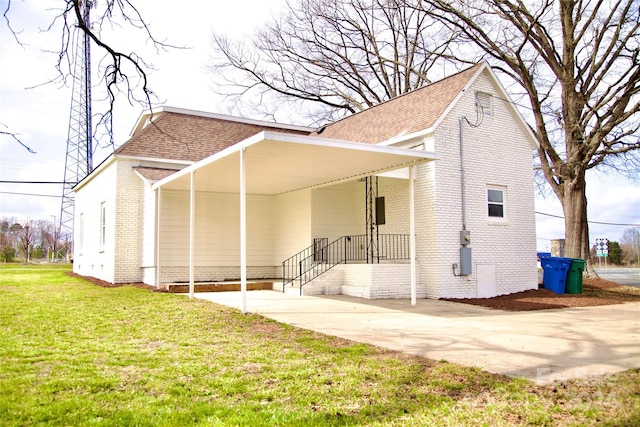 rear view of house featuring a carport and a yard