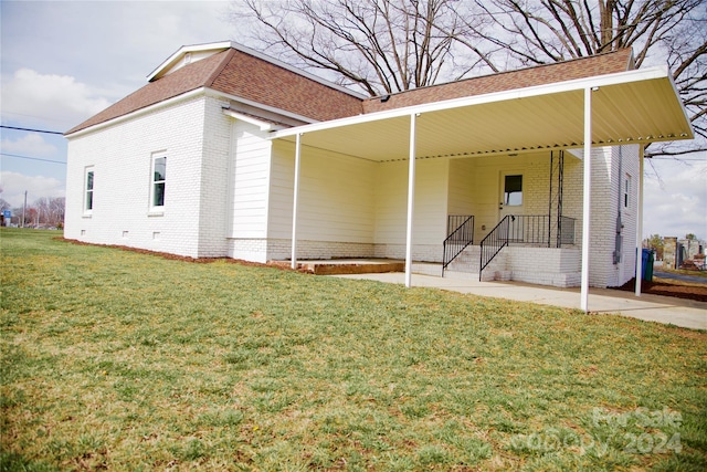 back of house with a lawn and a carport