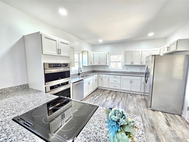 kitchen featuring white cabinets, appliances with stainless steel finishes, sink, and light hardwood / wood-style flooring