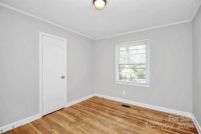 empty room with ornamental molding and hardwood / wood-style floors