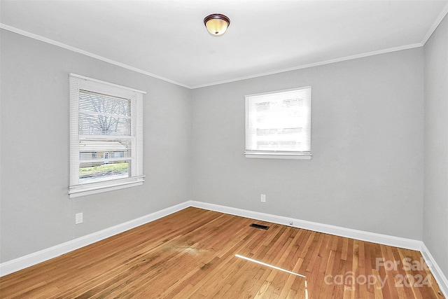 unfurnished room featuring ornamental molding, wood-type flooring, and plenty of natural light