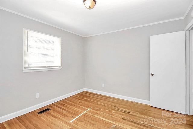 spare room with wood-type flooring and crown molding