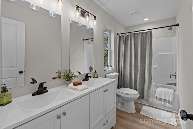 full bathroom featuring hardwood / wood-style floors, vanity, shower / bath combo, and toilet