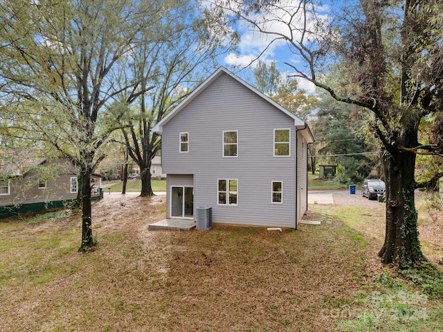 rear view of property with central air condition unit and a yard