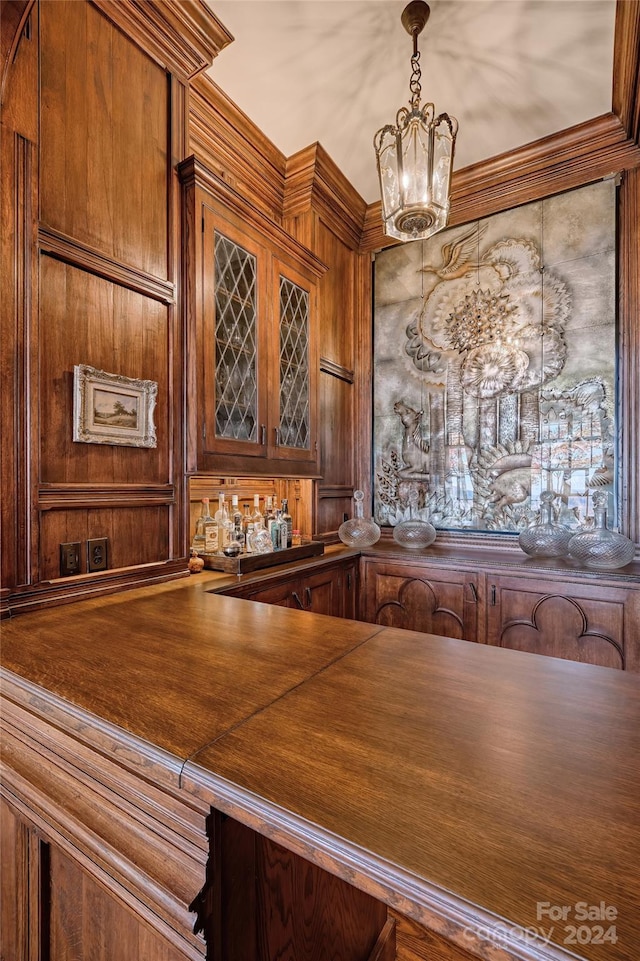 bar featuring a chandelier, pendant lighting, and ornamental molding