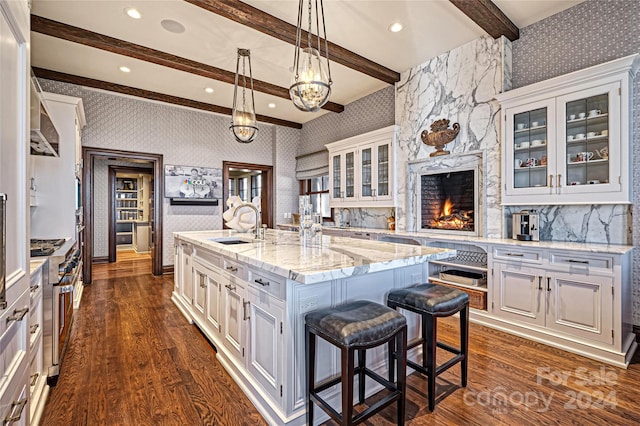 kitchen with a kitchen bar, a kitchen island with sink, and white cabinetry