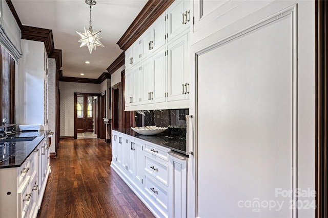 kitchen with pendant lighting, dark hardwood / wood-style flooring, sink, ornamental molding, and white cabinets