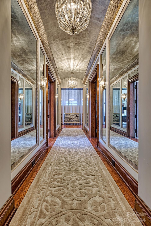 corridor featuring plenty of natural light, an inviting chandelier, and dark wood-type flooring