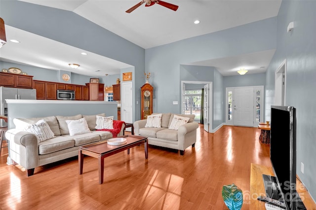 living room featuring ceiling fan, lofted ceiling, and light hardwood / wood-style floors