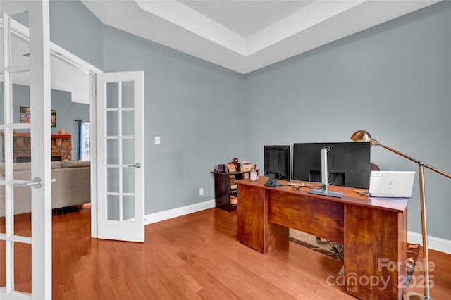 office featuring hardwood / wood-style flooring, a tray ceiling, and french doors