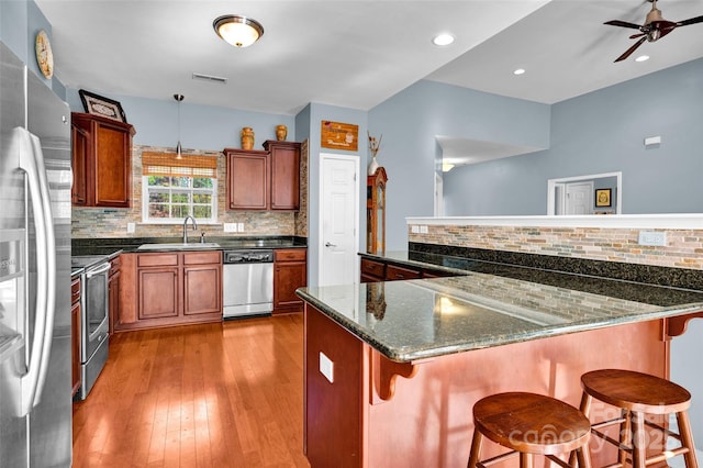 kitchen featuring dark stone countertops, sink, a breakfast bar area, and appliances with stainless steel finishes