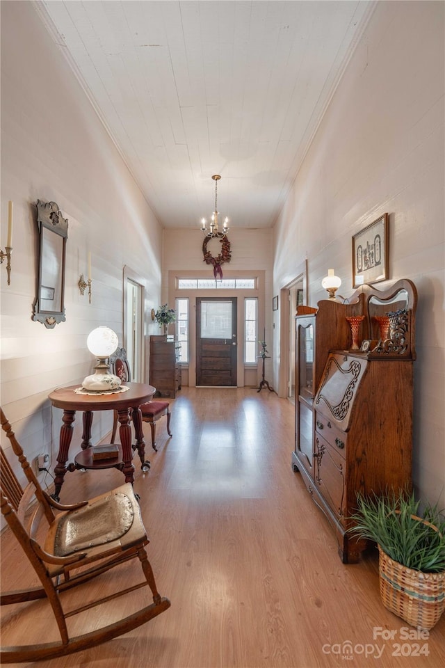 entrance foyer with crown molding, a chandelier, and light hardwood / wood-style floors