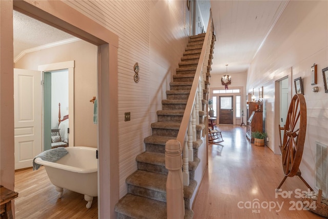 stairs featuring a chandelier, ornamental molding, and light wood-type flooring