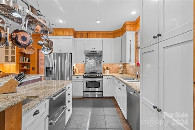 kitchen featuring appliances with stainless steel finishes, backsplash, light stone countertops, and sink