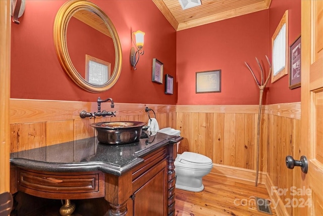 bathroom featuring wooden walls, toilet, large vanity, and hardwood / wood-style flooring