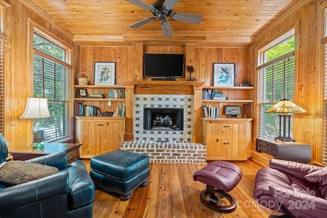 living room with a brick fireplace, wooden walls, wood ceiling, a healthy amount of sunlight, and light hardwood / wood-style flooring