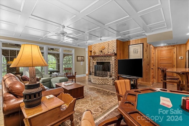 game room featuring coffered ceiling, a brick fireplace, brick wall, wooden walls, and ceiling fan