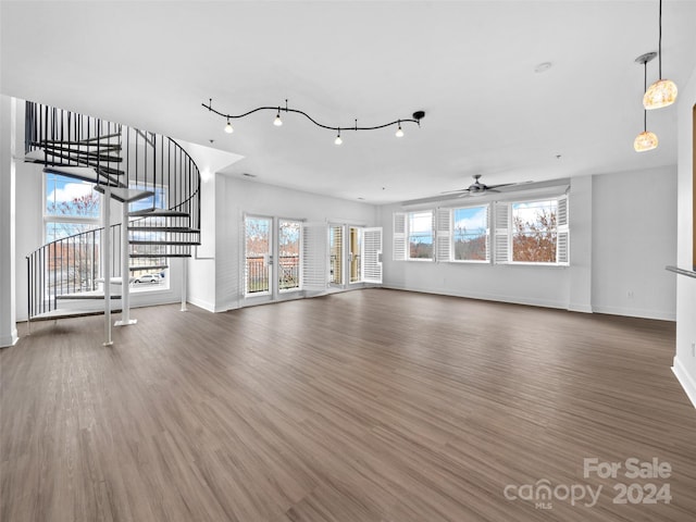 unfurnished living room with ceiling fan, dark hardwood / wood-style floors, and track lighting