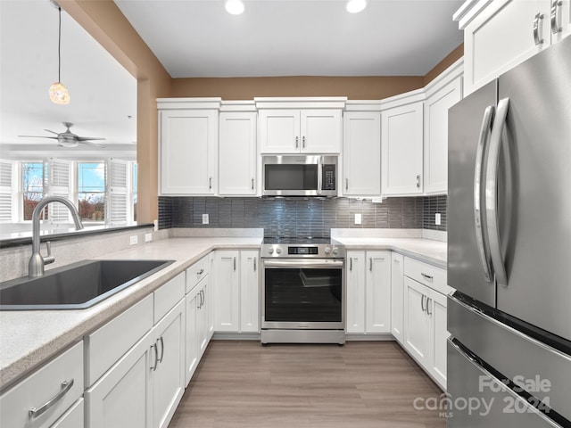 kitchen featuring ceiling fan, light hardwood / wood-style flooring, stainless steel appliances, and pendant lighting