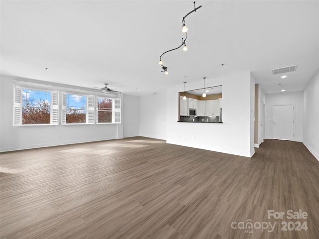 unfurnished living room featuring rail lighting, dark hardwood / wood-style floors, and ceiling fan