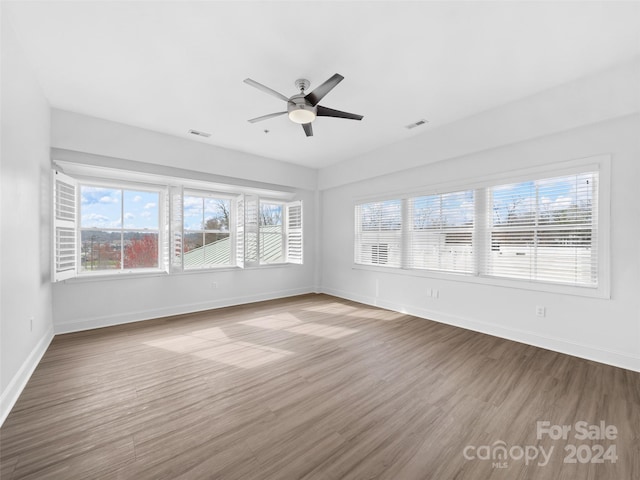 unfurnished room featuring plenty of natural light, dark hardwood / wood-style flooring, and ceiling fan