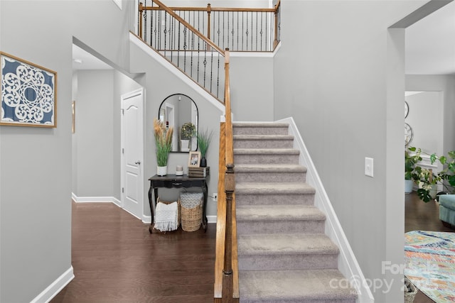 stairs featuring hardwood / wood-style flooring and a towering ceiling