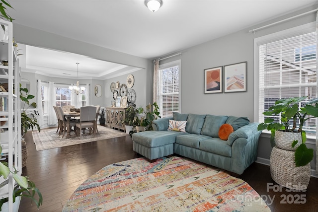 living room with dark hardwood / wood-style flooring, plenty of natural light, and an inviting chandelier