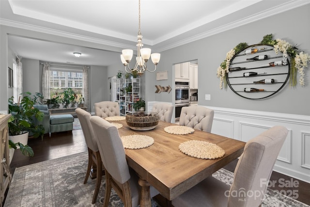 dining area with a tray ceiling, crown molding, a chandelier, and dark hardwood / wood-style floors