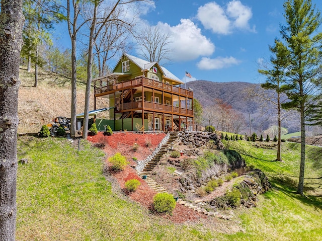 back of house with a yard and a deck with mountain view