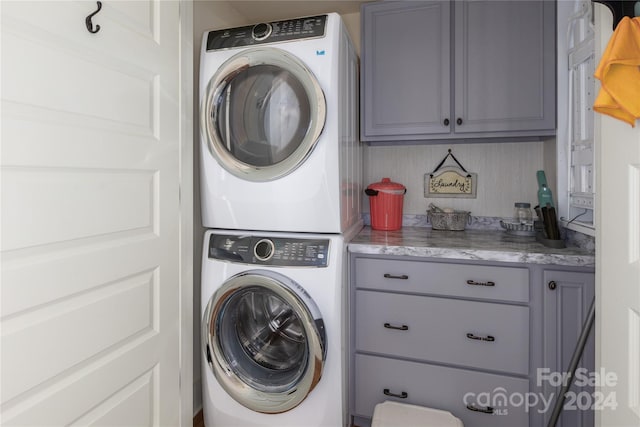 washroom featuring stacked washer and dryer and cabinets