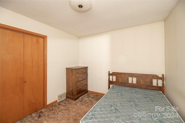 carpeted bedroom with a textured ceiling and a closet