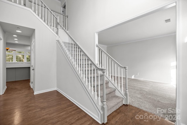 stairway with a high ceiling, ceiling fan, hardwood / wood-style floors, and crown molding