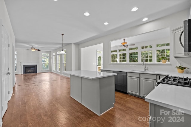 kitchen featuring dark wood-type flooring, a kitchen island, gray cabinets, decorative light fixtures, and sink