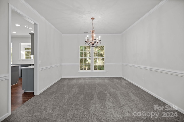 unfurnished dining area featuring ornamental molding, dark carpet, and a notable chandelier