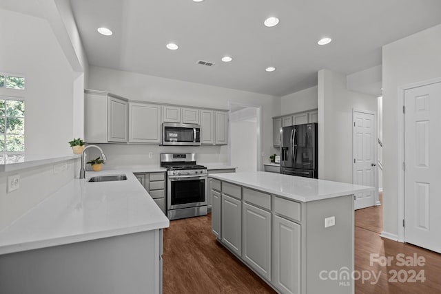 kitchen with gray cabinets, stainless steel appliances, a center island, dark hardwood / wood-style floors, and sink