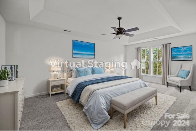 carpeted bedroom with a tray ceiling and ceiling fan