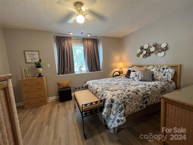 bedroom with a textured ceiling, ceiling fan, and light wood-type flooring