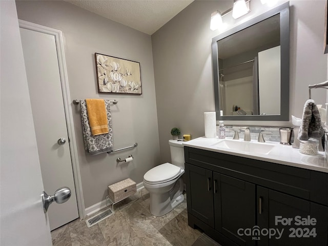 bathroom with vanity, a textured ceiling, tile floors, and toilet