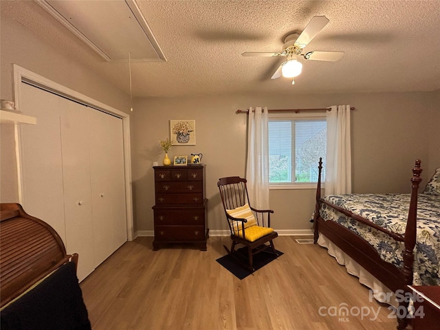 bedroom with light hardwood / wood-style flooring, ceiling fan, a closet, and a textured ceiling