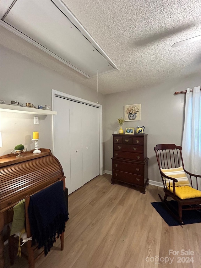 bedroom featuring a textured ceiling, light wood-type flooring, and a closet