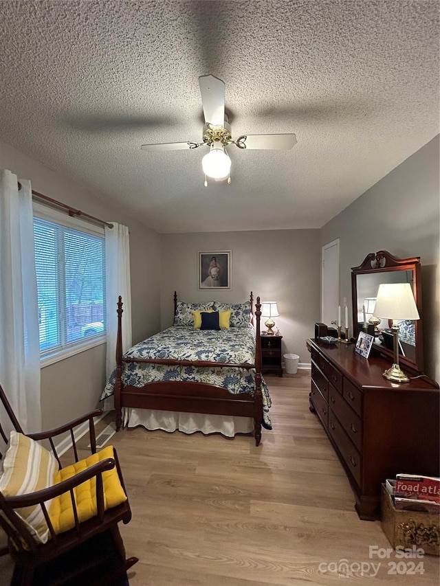 bedroom featuring light hardwood / wood-style floors, a textured ceiling, and ceiling fan