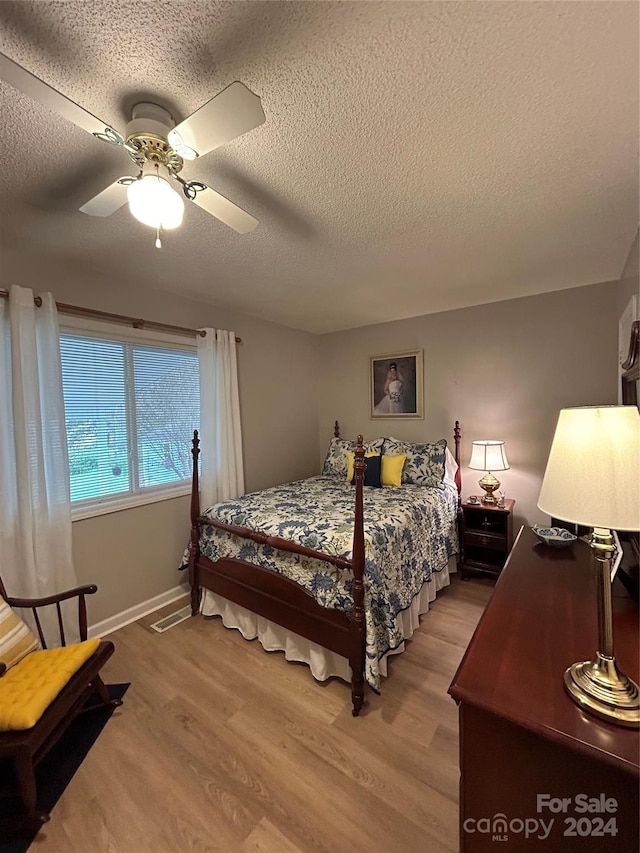 bedroom with a textured ceiling, light hardwood / wood-style floors, and ceiling fan