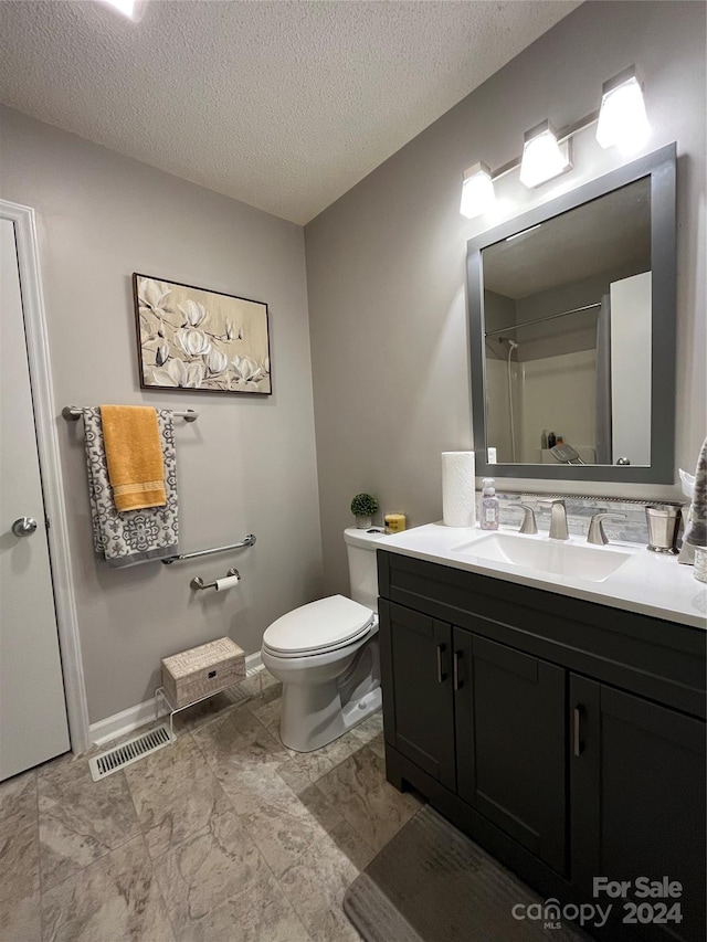 bathroom featuring toilet, a textured ceiling, vanity, and tile flooring