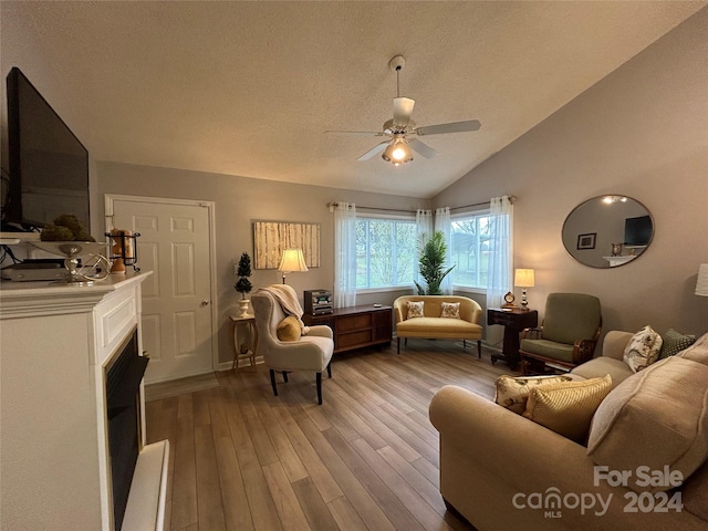 living room with a textured ceiling, ceiling fan, hardwood / wood-style flooring, and lofted ceiling