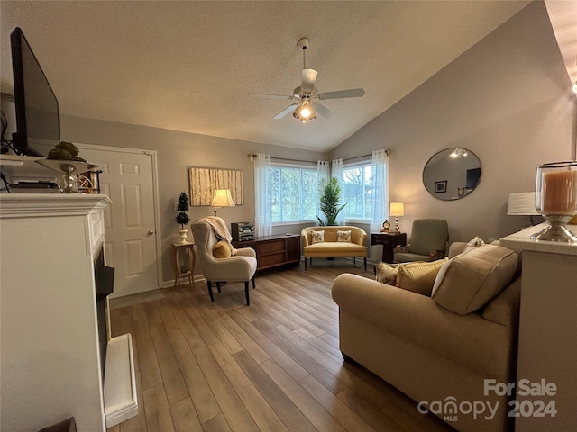 living room featuring ceiling fan, a fireplace, hardwood / wood-style flooring, and vaulted ceiling