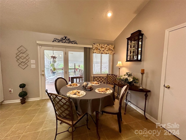 tiled dining space featuring vaulted ceiling