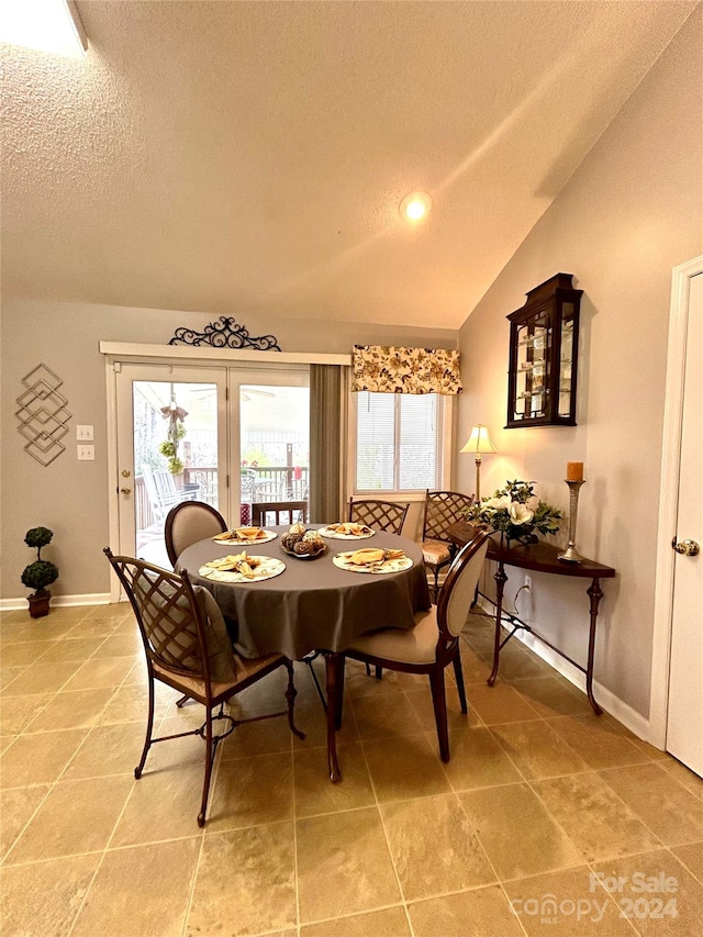 dining area with french doors, a textured ceiling, vaulted ceiling, and light tile floors