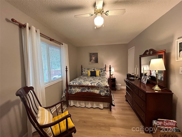 bedroom with a textured ceiling, ceiling fan, and light wood-type flooring