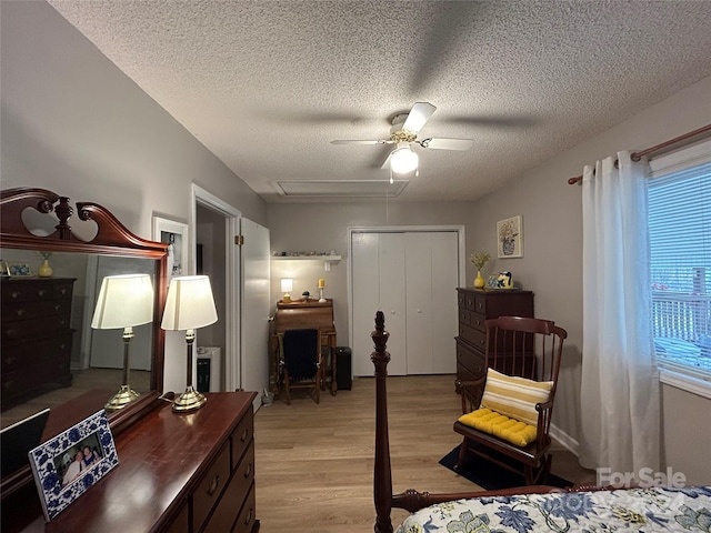 bedroom featuring light hardwood / wood-style floors, a closet, ceiling fan, and a textured ceiling